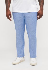 Lys blå, teksturerte bukser med slim fit og rett ben, kombinert med hvite sneakers med grå aksenter.