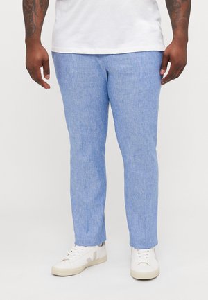 Light blue, textured trousers with a slim fit and a straight leg, paired with white sneakers featuring gray accents.