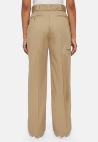 Beige wijde broek met hoge taille, met achterzakken en een klein logodeetail aan de zijkant, gemaakt van een gladde stof.