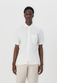 Camicia bianca a maniche corte in tessuto leggero, con colletto a punta, taschino sul petto e una vestibilità rilassata. Presenta dettagli di texture sottili.