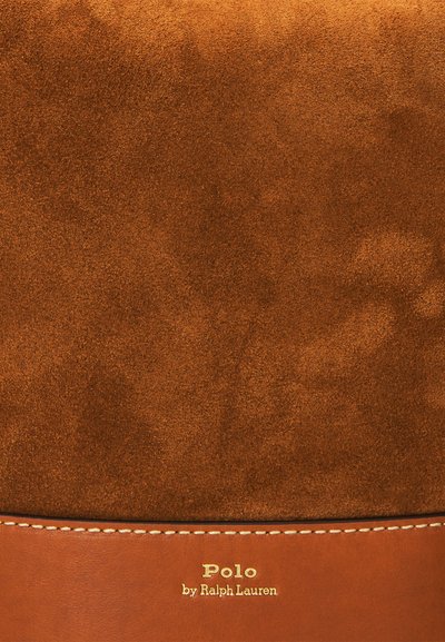 Brūnas zamša soma ar ādas apakšu un šuvju malām. Zelta "Polo by Ralph Lauren" logo apakšā. Visā somas virsmā mīksta tekstūra.