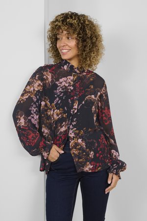Blusa fluida e trasparente nera con un motivo floreale in rosso, rosa e marrone. Presenta maniche lunghe e un colletto alto con dettagli a bottoni.