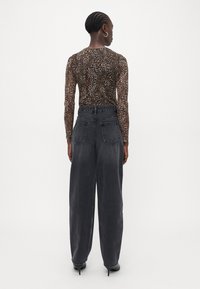 Brown leopard print long-sleeve shirt and high-waisted, loose-fit dark gray jeans with two back patch pockets, paired with black heels.