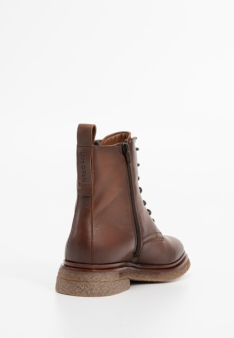 Braune Lederstiefelette mit einer strukturierten Korksohle, ausgestattet mit einem seitlichen Reißverschluss und Schnürsenkeln, entworfen für Stabilität und Komfort.