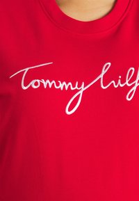 Rode katoen T-shirt met witte geborduurde tekst "Tommy Hilfiger" in cursieve stijl. Ronde halslijn met geribbelde afwerking. Soepele textuur.