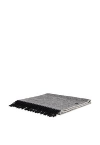 Kootud halli ja musta värvi viskab blanket, millel on tekstuuriga chevron muster ja äärtes frid, kokkutõmmatuna ja näidates peent sära.