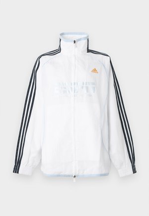 Bela Adidas jakna z zadrgo in visokim ovratnikom, črnimi tremi črtami na rokavih in oranžnim logotipom na prsih.