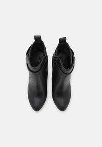 Bottes à cheville en cuir noir avec une texture lisse, bout pointu, fermetures éclair latérales et languettes à l'arrière pour un enfilage facilité.