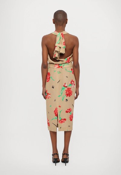 Rochie florală bej cu guler halter cu volane, având flori roșii și frunze verzi. Până la genunchi, cu o deschidere pe spate și o siluetă ajustată.