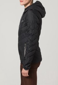 Veste matelassée noire à capuche avec motifs chevrons, poches latérales zippées et texture lisse. Conception légère et ajustée.