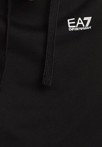 Svart hoodie med dragsko, tillverkad av mjukt tyg, med en vit logotyp "EA7 Emporio Armani" på bröstet.