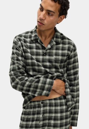 Conjunto de pijama a cuadros en negro y gris, hecho de tela suave. Camisa de manga larga con un bolsillo en el pecho, puños abotonados y pantalones a juego con botones.