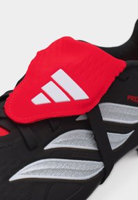 Μαύρο και κόκκινο ποδοσφαιρικό παπούτσι Adidas με λευκό λογότυπο και συνθετικό επάνω μέρος, με υφασμένα πάνελ και ελαστικά μαύρα κορδόνια.