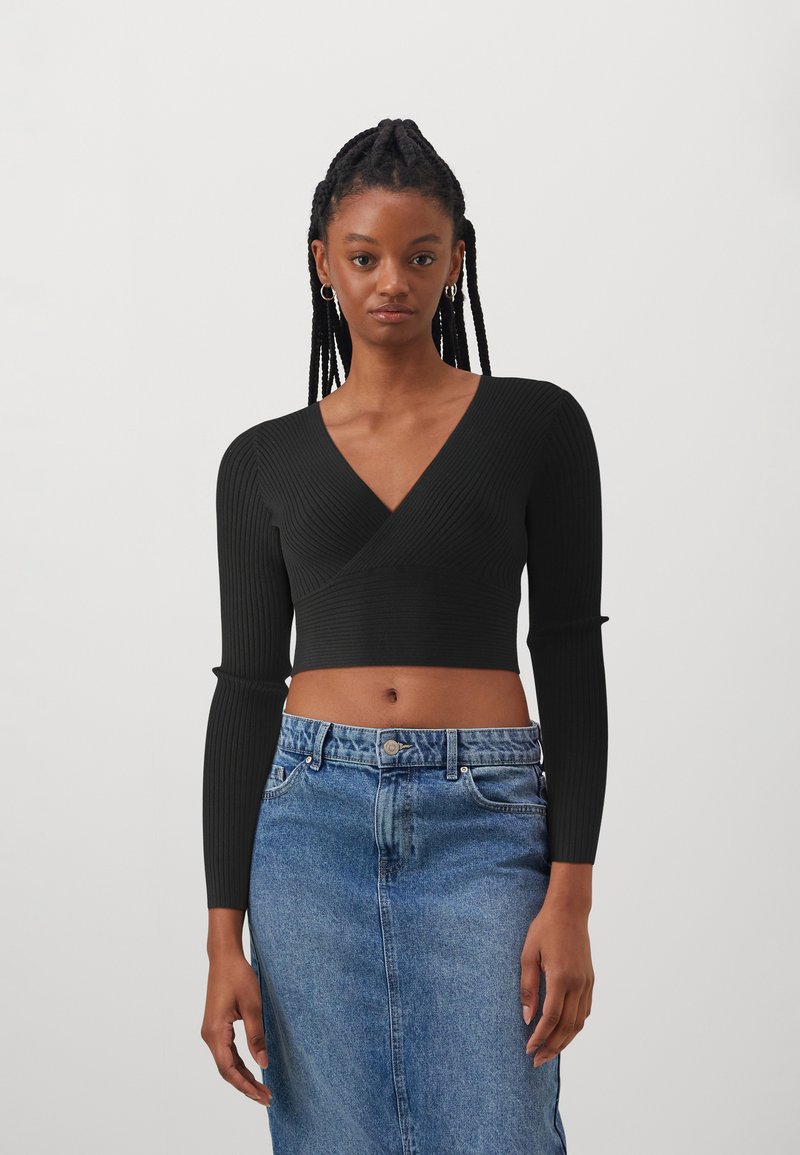 Schwarzes, geripptes Langarm-Crop-Top mit tiefem V-Ausschnitt, kombiniert mit einem hochtaillierten blauen Jeansrock. Texturiertes Material, figurbetonte Silhouette.