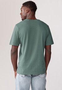 Grön bomull T-shirt med rundad halsringning och korta ärmar. Har en mjuk textur och en avslappnad passform. Inga synliga grafiker eller mönster.