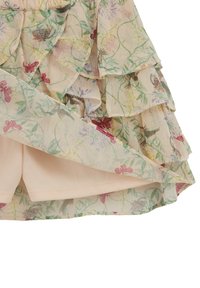 Jupe beige clair à plusieurs couches avec un tissu superposé imprimé de fleurs et de papillons et une doublure intérieure beige uni.