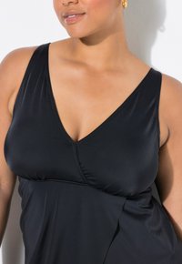 Svart baddräkt för kvinnor med djup V-ringning, ärmlös design och mjukt, elastiskt tyg med gathered bust-detalj.