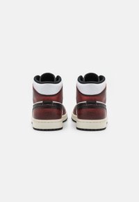 Höga sneakers med en texturerad röd och svart ovandel, vit krage, svarta accenter och en krämfärgad sula.