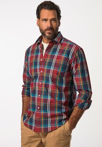 Camicia a quadri rossa e blu con bottoni bianchi, maniche lunghe e vestibilità rilassata. Presenta righe a contrasto in arancione e turchese.