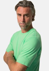 T-shirt vert menthe à manches courtes en coton, avec un col rond et un logo discret en relief sur la manche.