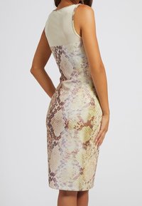 Robe ajustée sans manches avec un haut de couleur claire et un imprimé serpent multicolore sur la partie inférieure. Texture lisse, longueur genoux.