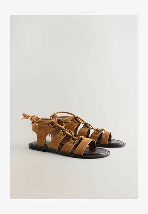 Bruine suède gladiator sandalen met open tenen, meerdere banden en een gestrikt enkel detail. Rubberzool met een gladde textuur.