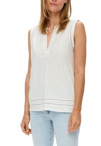 Sleeveless white top with a v-neckline, textured fabric, and decorative horizontal cut-outs near the hem; relaxed fit.