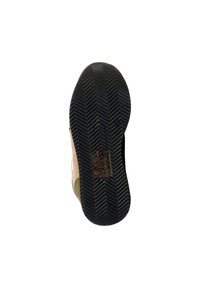 Semelle de chaussure avec un motif en chevrons, en matériau en caoutchouc noir avec des accents marron clair, et des icônes en relief pour les instructions d'entretien.