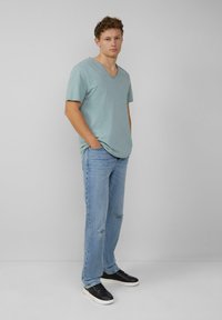 Jasnoniebieska, krótko-sleeve koszulka typu v-neck w połączeniu z jasnoniebieskimi zniszczonymi dżinsami i czarnymi trampkami, charakteryzująca się luźnym krojem i casualowym stylem.