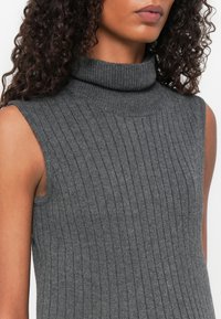 Pilkas berankovis megztinis su aukštu apykakle, raukšlėtu audiniu, turintis glotnų paviršių, tinkantis sluoksniavimui.