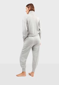 Grijze fleecetrack suit met een hoge kraag, ribgebreide manchetten en tailleband. Lijkt een relaxte pasvorm te hebben, met taps toelopende broekspijpen en een zachte textuur.