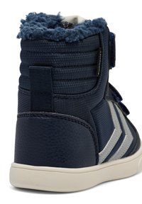 Granatowy wysoki sneakers z teksturowanym skórzanym obcasem, miękką wyściółką z polaru i kontrastującymi szarymi akcentami na gumowej podeszwie.