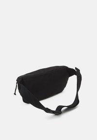 Svart tygslingväska med rektangulär form, justerbar rem och dragkedjestängning. Slät textur med minimalistisk design.