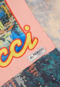 Colț de material roz cu text îndrăzneț galben și roșu și eticheta Fiorucci Milano pe un fundal abstract multicolor.