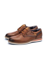 Zapatos de cuero marrón con cordones naranjas, punta redonda, suela blanca con acentos en rojo y azul, y detalle de costura contrastante en los bordes.