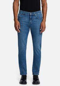 Jeans blue in denim con vestibilità dritta, caratterizzati da cinque tasche, passanti per cintura e una leggera sbiaditura. Abbinati a scarpe nere.