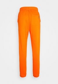 Helle orange Sweatpants mit einem elastischen Bund und einer einzigen aufgesetzten Tasche auf der rechten hinteren Seite, präsentiert vor einem schlichten Hintergrund.