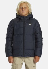 Námořnická modrá zateplená bunda se zapínáním na zip, kapucí a logem. Vyrobena z hladkého materiálu s prošívanou strukturou, má elastické manžety a lem.