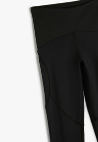 Zwarte legging met een hoge tailleband, een gladde textuur en contrasterende stiksels. Heeft een aansluitend ontwerp en naadloze zijkantdetails.