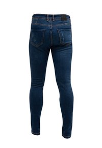 Jeans ajustados en denim azul oscuro con una textura desgastada. Presenta dos bolsillos traseros y una etiqueta de cuero en la cinturilla.