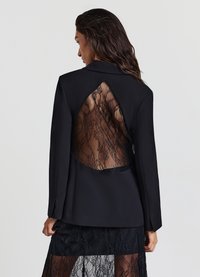 Schwarzer Blazer mit einem Rückenausschnitt und Spitzenbesatz. Maßgeschneiderter Schnitt, Reverskragen und glatte Stofftextur.