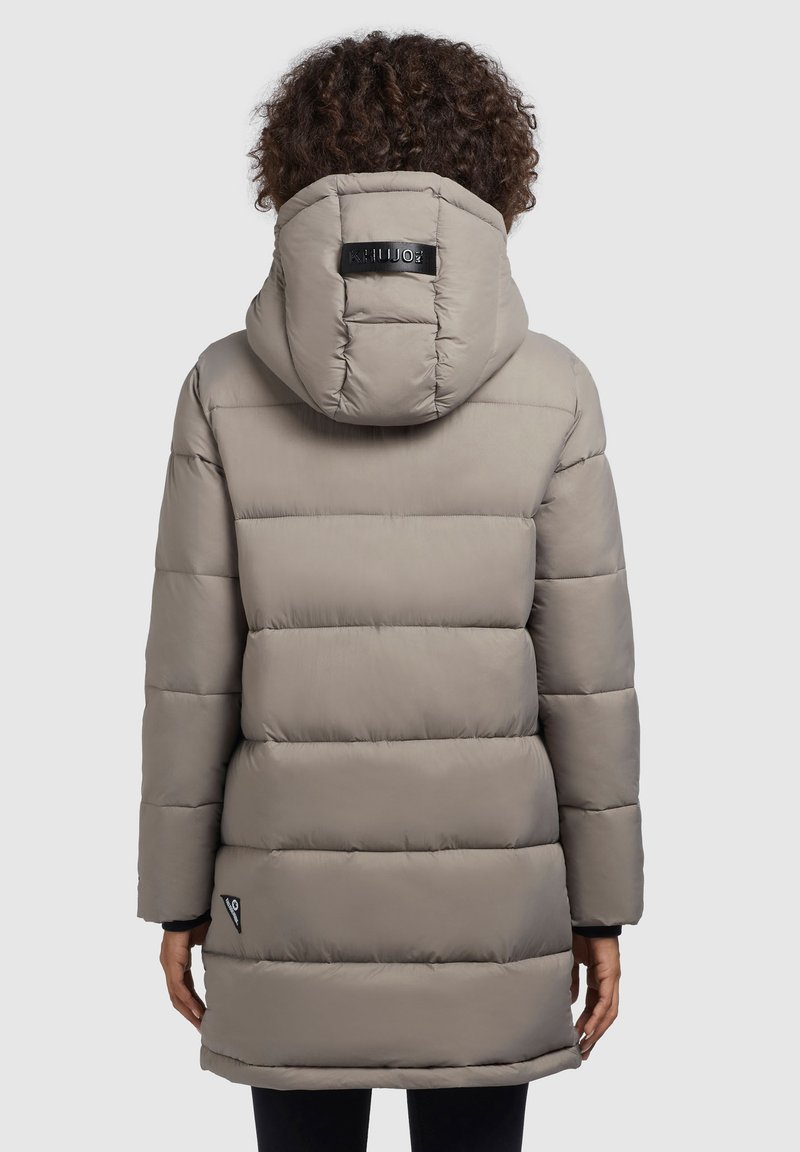 Padded parka w kolorze jasnoszarym, z kapturem i czarną naszywką logo, z poziomym przeszyciem i długością sięgającą kolan.