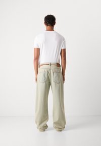 Light green denim pants with a loose fit, featuring two back pockets and a brown woven belt, paired with a fitted white t-shirt.