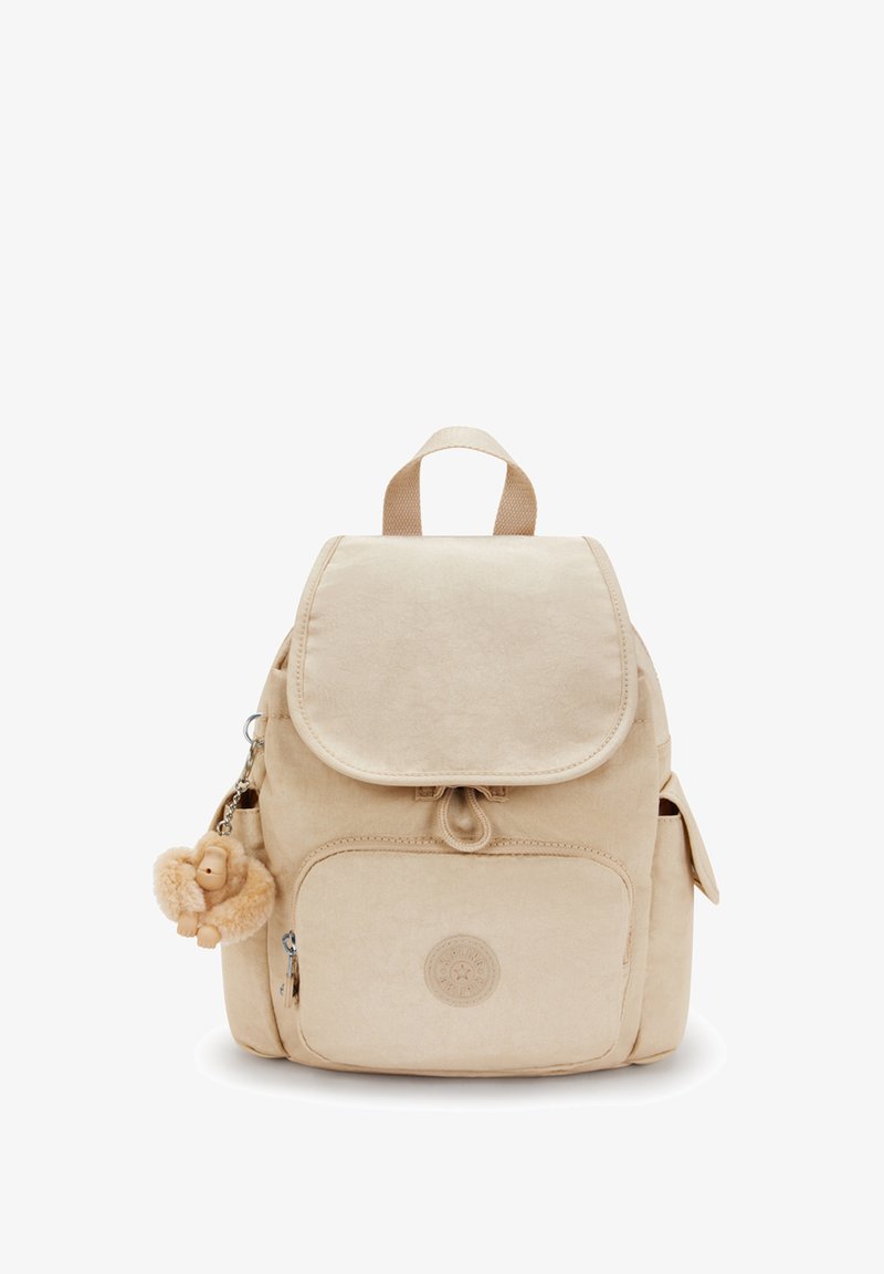 Zaino in tessuto beige con chiusura a patta, tasca anteriore e tasche laterali. Presenta un grazioso charm in peluche e un badge con il logo sul fronte.