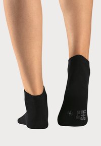 Schwarze Knöchelsocken mit geripptem Bund, die einen engen Sitz und verstärkte Ferse bieten. Zeigen weißes Branding und einen kleinen Größenindikator an der Seite.