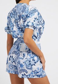 Jumpsuit de patrón floral azul con mangas cortas, cintura elástica y corte holgado. Fabricado en un tejido ligero con una textura suave.