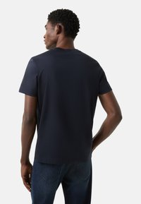 Tmavě modré tričko s krátkým rukávem z měkké látky, s kulatým výstřihem a rovný střihem, zobrazené zezadu.