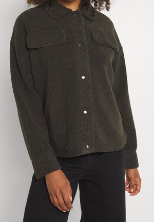 Ciemnozielona polarowa kurtka koszulowa z kołnierzem, dwiema kieszeniami na piersi, zapięciem na zatrzaski oraz miękką, teksturowaną powierzchnią. Długie rękawy z mankietami na guziki.