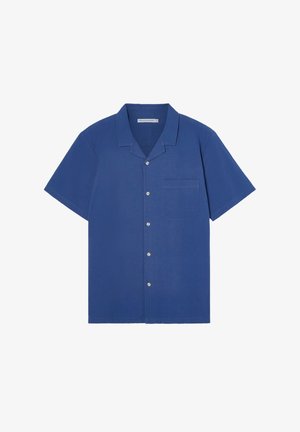 Camisa de manga corta abotonada en azul oscuro, de tejido texturizado, con un bolsillo en el pecho y botones blancos. Diseño con cuello y corte relajado.