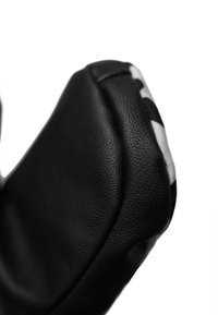 Schwarzes Lederhandschuh mit strukturierter Oberfläche, runder Form und weißen Akzenten an der Unterseite. Nahaufnahme hebt die Materialqualität hervor.